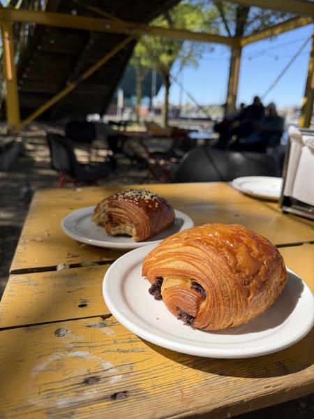 Two croissants on a yellow wooden table in an outdoor cafe